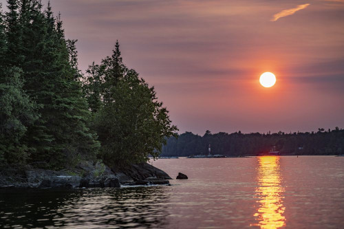 Blazing sun reflected on water along a coastline at sunset Poster Print by Keith Levit (20 x 13)