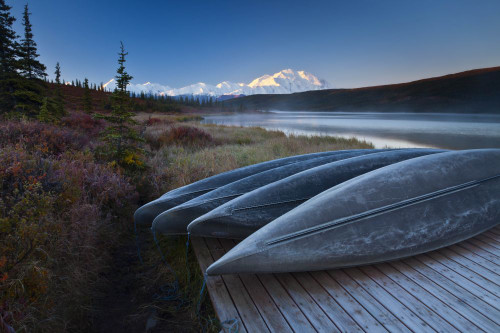 Canoes lined up on a dock at Wonder Lake in front of Mt. McKinley. Poster Print by Ralph Lee Hopkins (18 x 12)