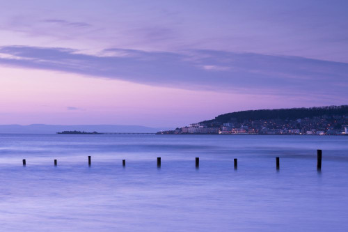 The seaside town of Weston-super-Mare from Uphill beach at dusk with Birnbeck Pier in the distance. Poster Print by Loop Images Ltd. (20 x 13)