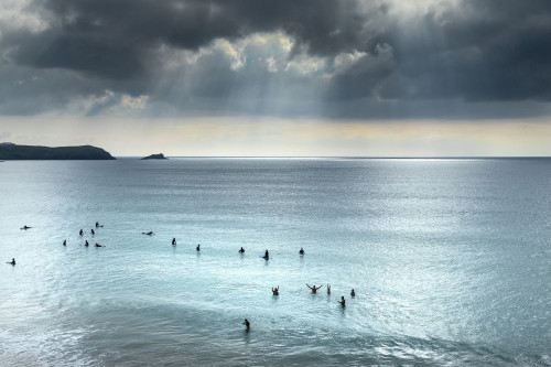 Surfers waiting for a wave on a calm sea at Fistral in Newquay in Cornwall. Poster Print by Loop Images Ltd. (17 x 11)