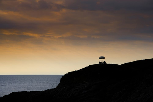 Late evening light over a picnic table and an umbrella on Towan Head in Newquay in Cornwall. Poster Print by Loop Images Ltd. (20 x 13)
