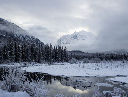 Snow covers the mountainous and forested landscape in Chugach State Park; Eagle River, Alaska, United States of America Poster Print by Alex Rearick (18 x 14)