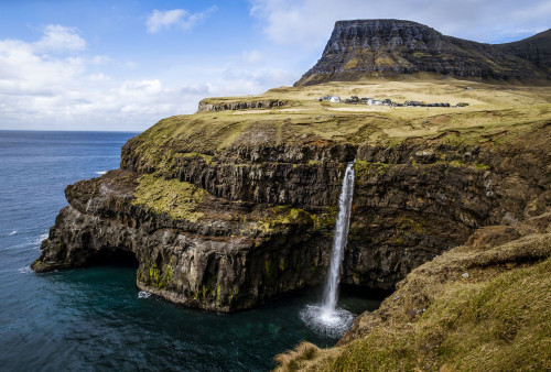 A waterfall cascades down a dramatic rockface on the Faroe Islands. Poster Print by Loop Images Ltd. (19 x 13)