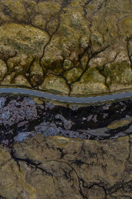 An aerial view shows a road passing through stunning textured landscapes on the Faroe Islands. Poster Print by Loop Images Ltd. (12 x 18)