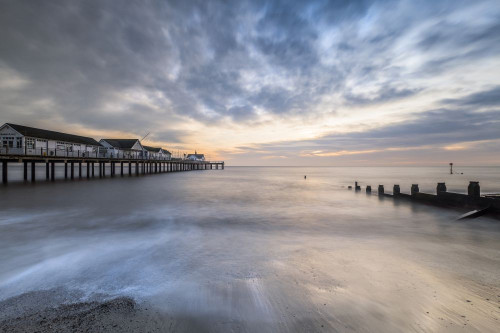 Southwold pier in Suffolk looking in between one of the sea defences on the sandy beach. Poster Print by Loop Images Ltd. (20 x 13)