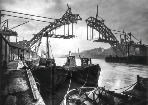 Building Newcastle Bridge in 1926 over the river Tyne. Boats and tugs moored at quaysaide. Cranes on bridge. Poster Print by John Short (19 x 13)
