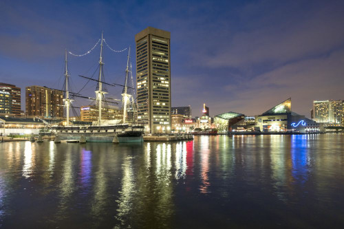The USS Constellation with the Baltimore World Trade Center and Baltimore harbour at night. Poster Print by Loop Images Ltd. (20 x 13)