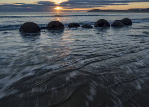 Incoming tide at sunrise with the Moeraki boulders in the surf along a stretch of Koekohe Beach on the South Island of New Zealand; Hampden, North Otago, New Zealand Poster Print by Michael Melford (16 x 12)