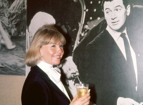 Doris Day side view smiling next to poster of Rock Hudson, undated. Photo: Oscar Abolafia (DORISDAY3) Poster