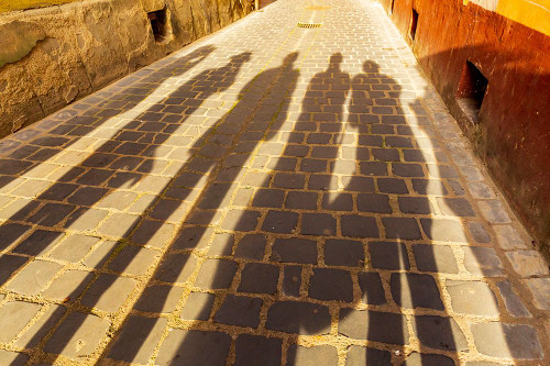 Romania-Brasov Shadowed figures in silhouette on street cobblestone Poster Print - Emily M. Wilson