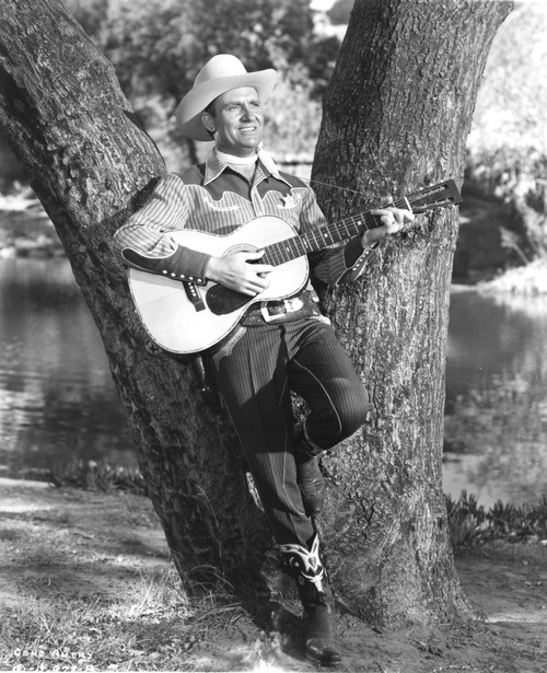 Gene Autry playing guitar against a tree Photo Print - Item # VARCEL681209