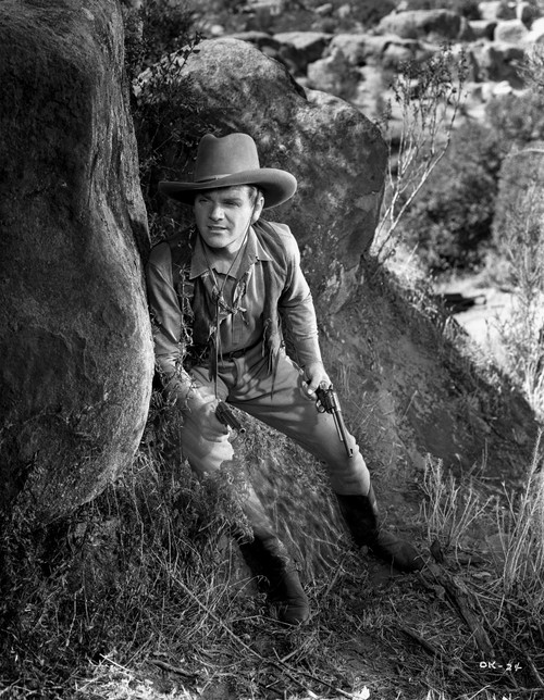 James Cagney Sneaking Behind a Big Rock in Long Sleeve Shirt and Cowboy Hat with Pistol on Hand Photo Print - Item # VARCEL683279
