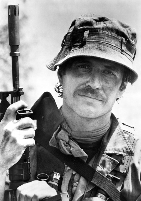 Tom Berenger carrying a gun outdoors Photo Print - Item # VARCEL684919