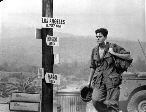 Film still of Charlie Sheen wearing a military uniform walking past sign posts Photo Print - Item # VARCEL684983