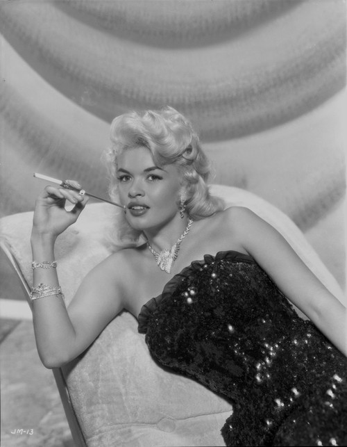 Jayne Mansfield sitting on the White Silk Couch in Black Sequin Strapless Dress and Pearl Necklace with Right Hand Holding a Cigarette Photo Print - Item # VARCEL685409