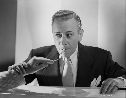 George Raft in Black Suit Lighting a Cigarette Photo Print - Item # VARCEL687016