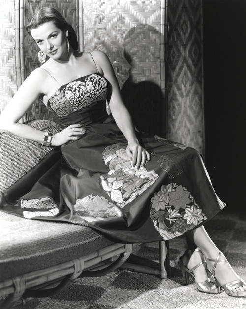 Jane Russell Posed in Silk Floral Strap Dress and Bead Bracelet while Seated on a Couch with Right Hand on the Waist and Left Hand on the Lap Photo Print - Item # VARCEL687478