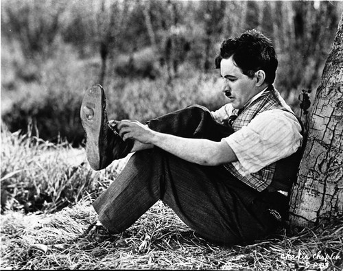 A film still of Charlie Chaplin putting on a shoe Photo Print - Item # VARCEL688055