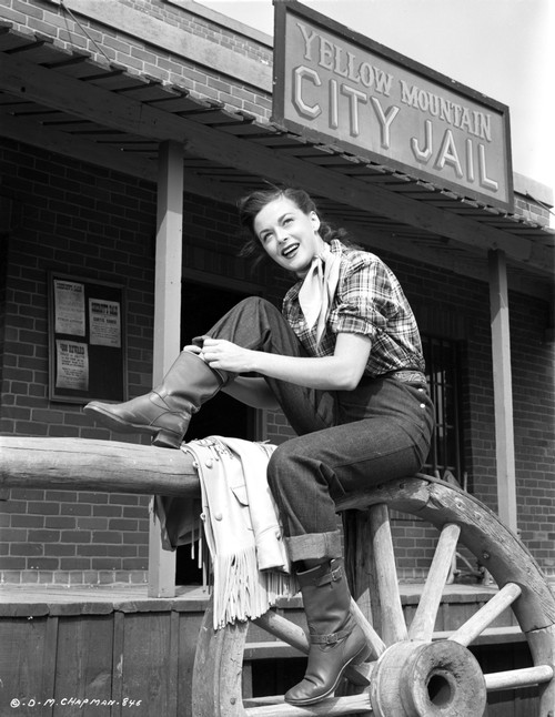Marguerite Chapma sitting on Wooden Fence, wearing Checkered Polo and Black Pants with Boots Photo Print - Item # VARCEL696102