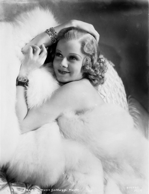 Jean Harlow Posed and sitting on a White Couch in White Fur Pelt Shoulder Dress and Fur Coat with Hands Together Photo Print - Item # VARCEL697065