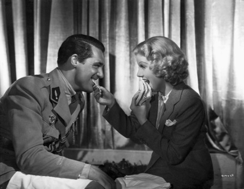 Jean Harlow Scene from a Film sitting on Couch in Black Tweed Linen Suit Dress while Talking to a Man in Military Uniform Photo Print - Item # VARCEL697246