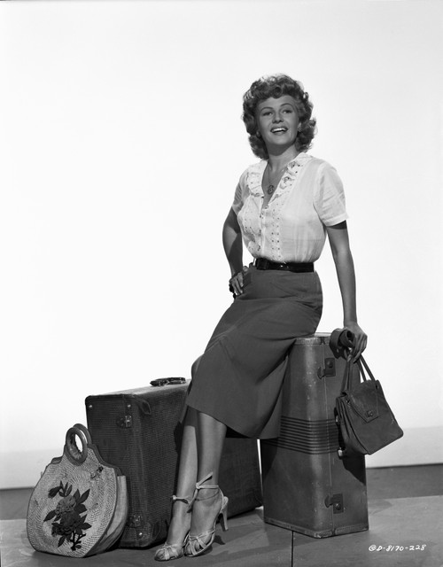 Rita Hayworth sitting on the Luggage with a Hand on Waist Pose Photo Print - Item # VARCEL698437