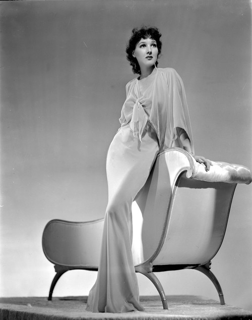 Jean Parker Posed in White Broad Sleeve Silk Dress and Fishtail Skirt with Left Hand on the Top Railing of a Couch Photo Print - Item # VARCEL702936