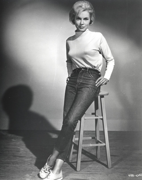 Janet Leigh sitting on the Chair in White High Neck Long Sleeve Linen Shirt and Black High Waist Tight Pants with Legs Crossed and Hands on the Waist Photo Print - Item # VARCEL690207