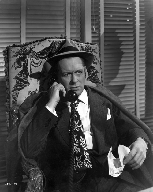 Robert Montgomery sitting in Black With Hat - film still Photo Print - Item # VARCEL692684
