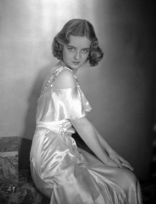 Bette Davis Seated with Hands Together on the Knee in White Beaded Strap Silk Dress Photo Print - Item # VARCEL692888