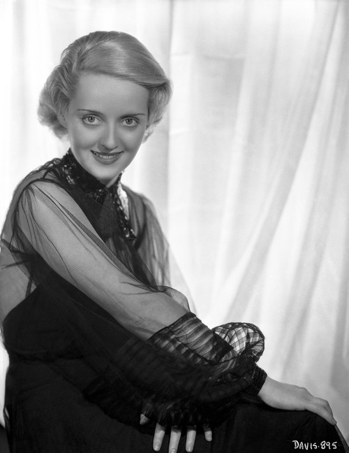Bette Davis Seated with Arms Cross and Hands Laid on the Lap in Black Sheer Long Sleeve Dress Photo Print - Item # VARCEL693126