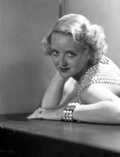 Bette Davis Portrait Leaning on the Table with Hand on the Head in Beaded Sleeveless Shirt and Pearl Bracelet Photo Print - Item # VARCEL693151