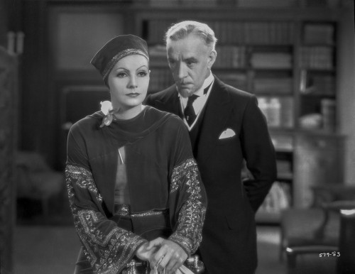 Greta Garbo Listening to a Man in Formal Outfit Photo Print - Item # VARCEL693250