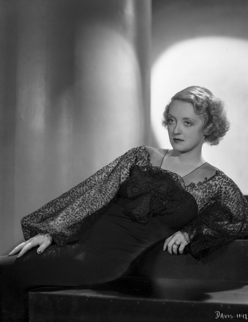 Bette Davis Reclining on the Table with Hand on the Skirt in Black Sheer Lace Long Sleeve Dress Photo Print - Item # VARCEL693286