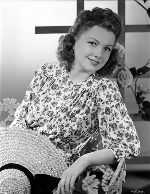 Anne Baxter posed on Floral Dress sitting and smiling Photo Print - Item # VARCEL693892