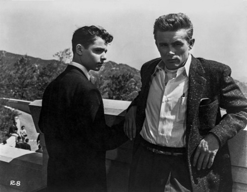James Dean Seated on a Chair in White Long Sleeve Collar Shirt and Black Linen Pants with Knees Bent and Head Leaning on the Hand Photo Print - Item # VARCEL694146