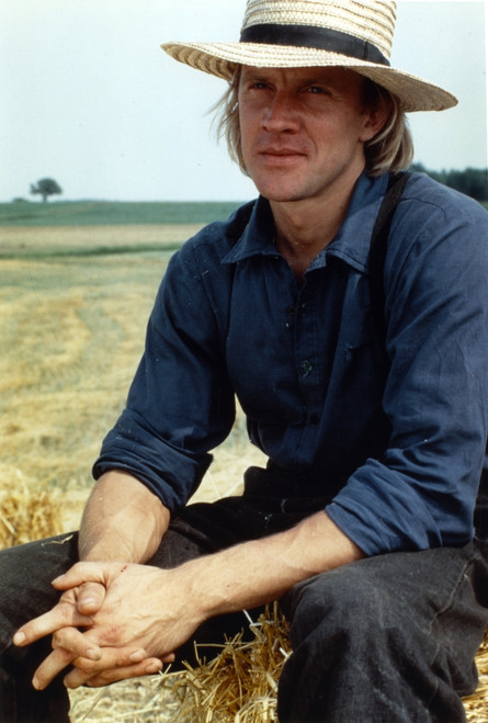 Alexander Godunov sitting on a Hay Stack wearing Blue Long Sleeves and a Hat Photo Print - Item # VARCEL694868