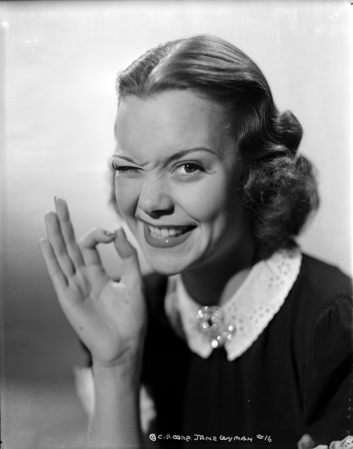 Jane Wyman Portrait in White Collar and Black Velvet Short Sleeve Dress with Right Eye Winked and Right Hand in OK Hand Gesture Photo Print - Item # VARCEL705821