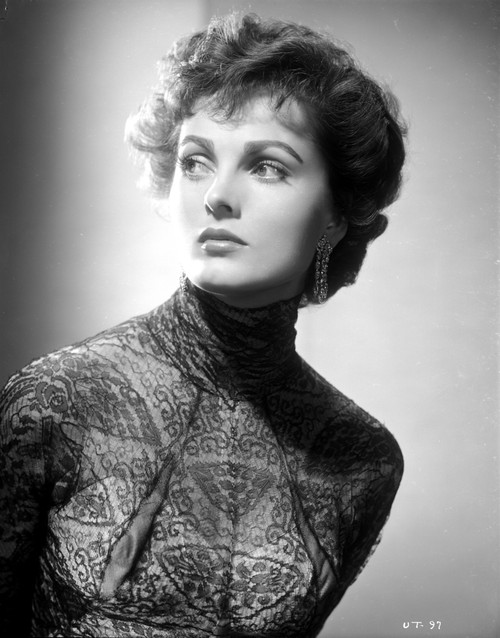 Ursula Theiss peering away from the camera, wearing a long-sleeve, turtle neck dress, with intricate patterns sewn into the lace Photo Print