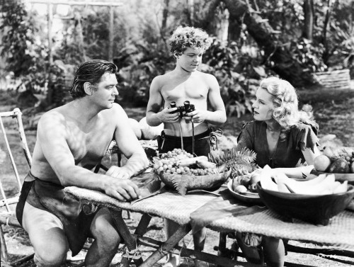 Johnny Weissmuller Eating on the Table with a Woman and a Boy in a Movie Scene Photo Print - Item # VARCEL709298