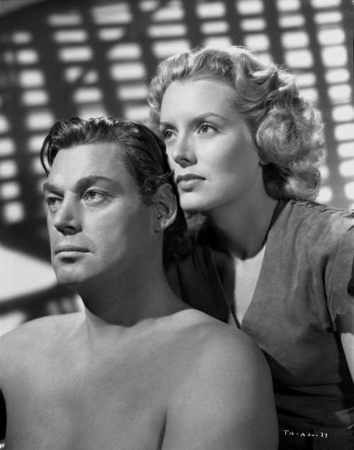 Johnny Weissmuller sitting with a Woman standing in His Back in a Classic Movie Scene Photo Print - Item # VARCEL709378