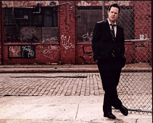 Dean Winters In Suit Leaning On Fence Photo Print