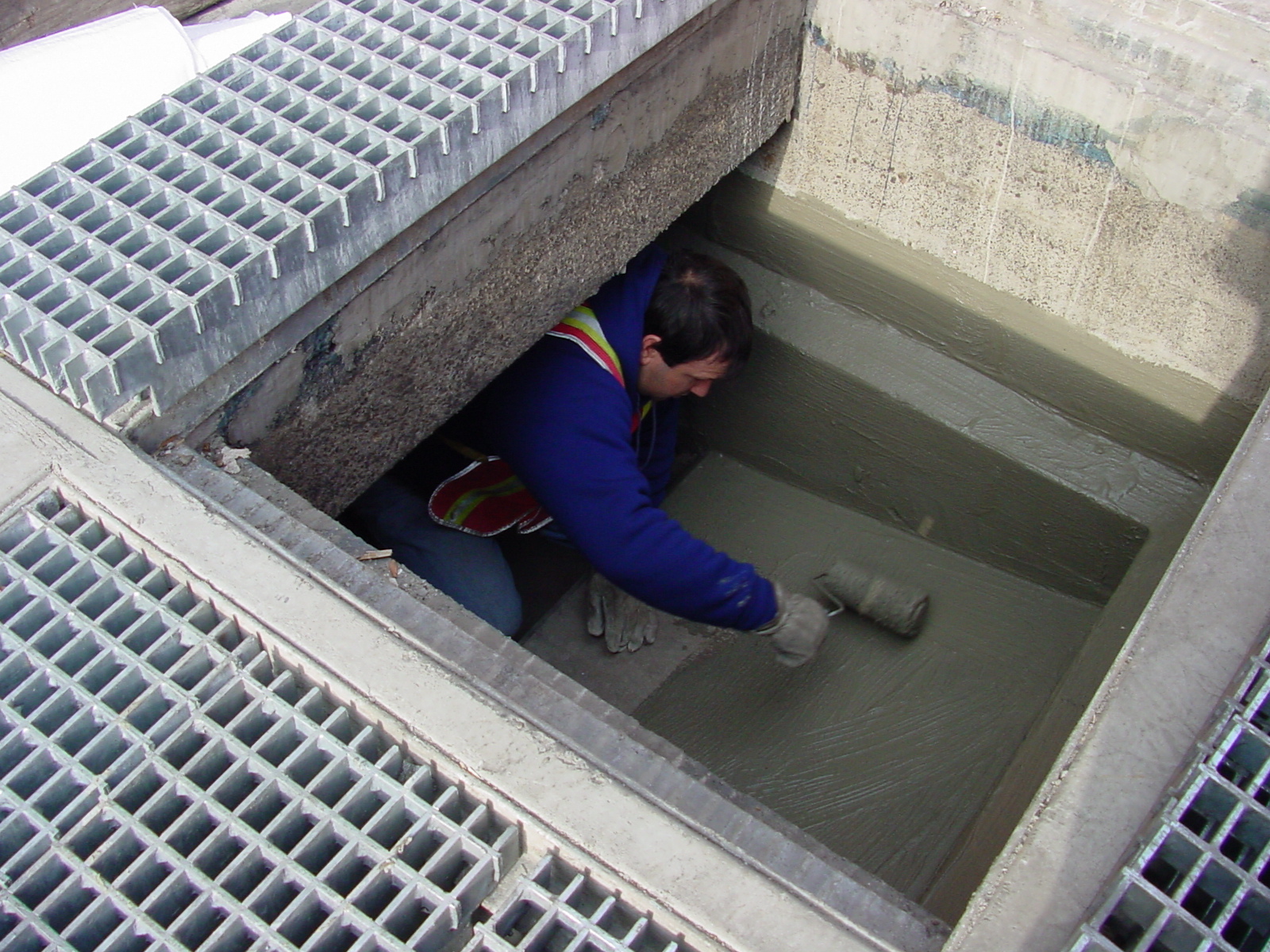 Man working in a floor opening to repair concrete  below water level. 