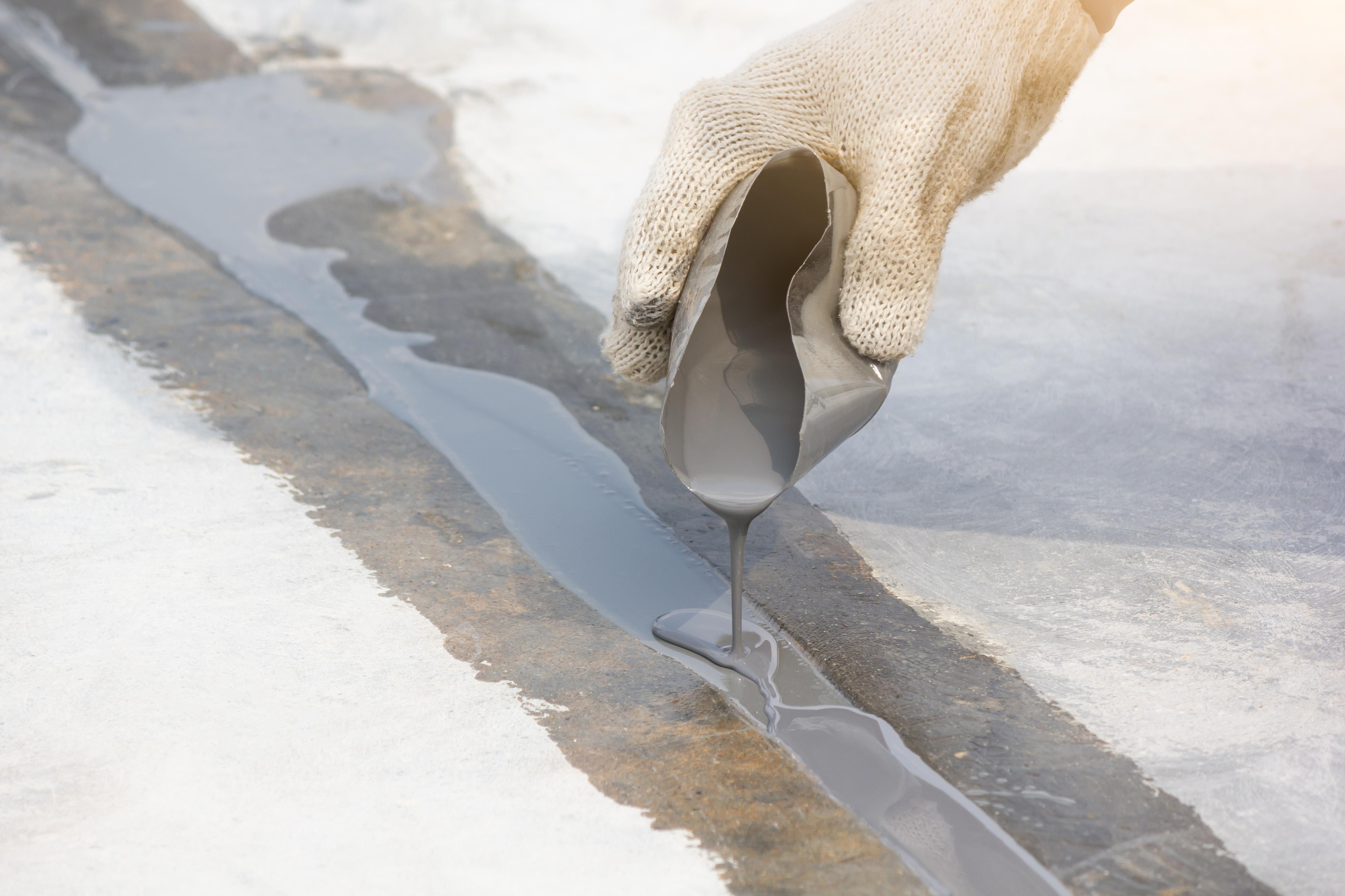 Applying concrete filler to repair a crack in a concrete floor.