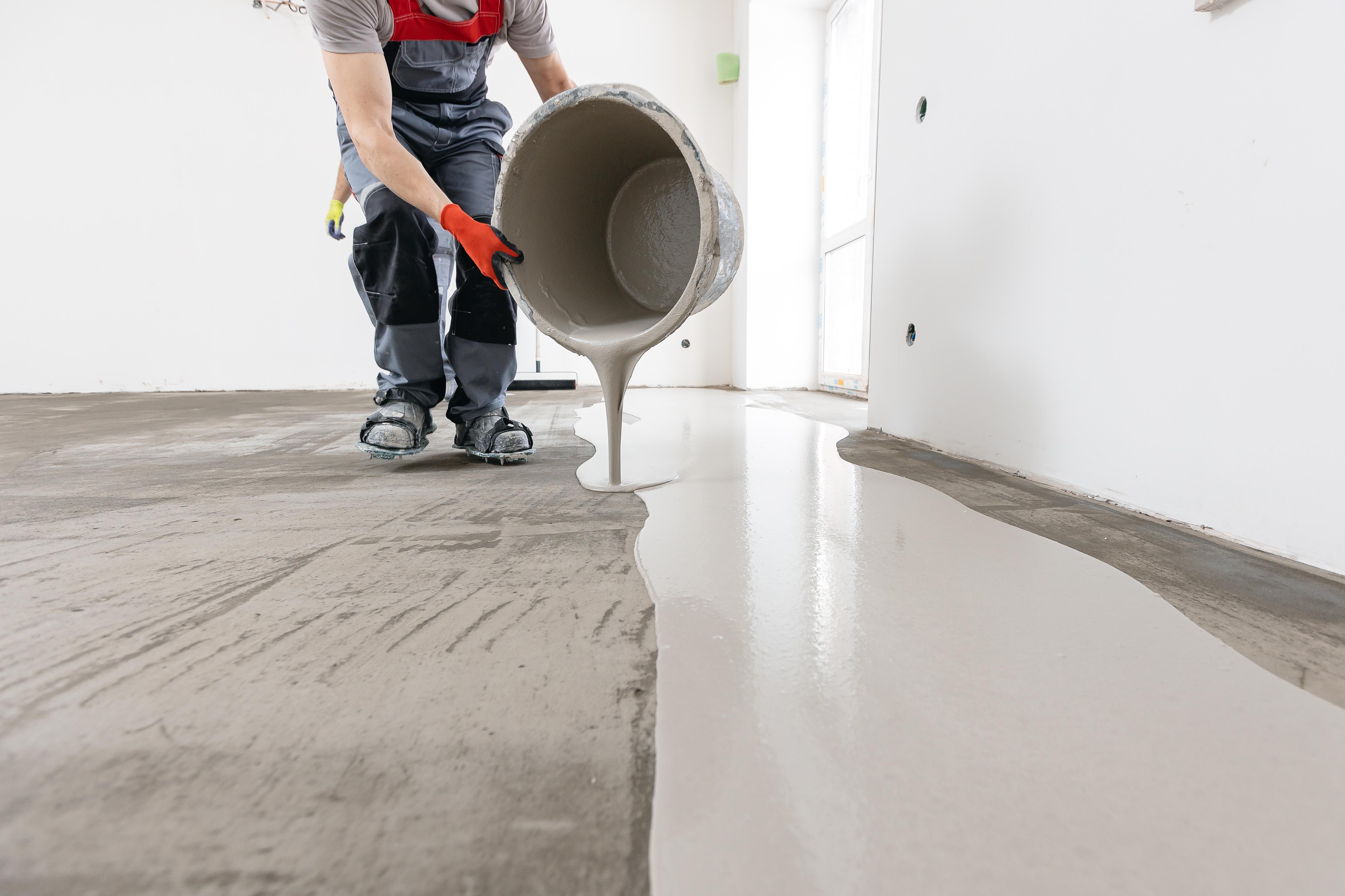 Man pouring repair coating onto a concrete floor.