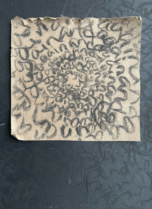 original abstract word art using the word "again" in a round never-ending swirl, created with black charcoal on recycled dark beige cardboard, and mounted on black recycled mat board on which "again" is written also in a near-circle.