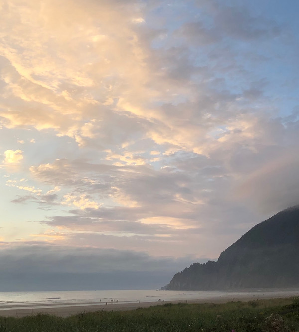 sunset on silver blue ocean, mountain, golden clouds, and people on the beach