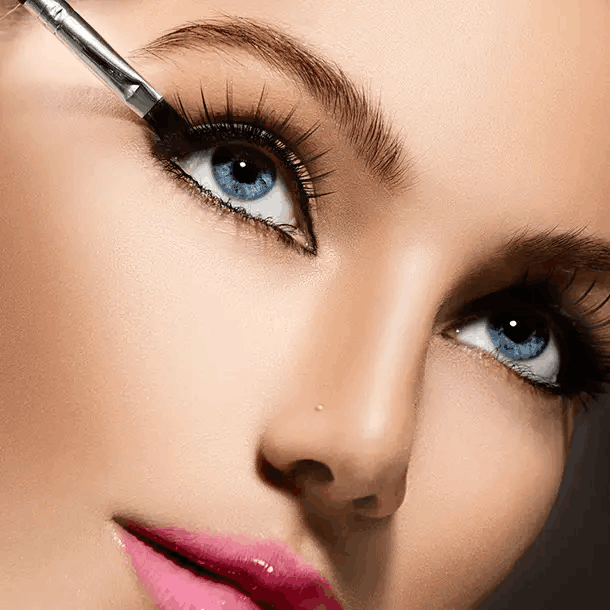 A woman with striking blue eyes carefully applies mascara to enhance her lashes and create a captivating look.