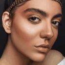 Stylish woman with a gold headband and makeup, showcasing a glamorous look.