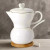 A cute white coffee pot on a wooden stand, perfect as a wedding or bridal shower favor.